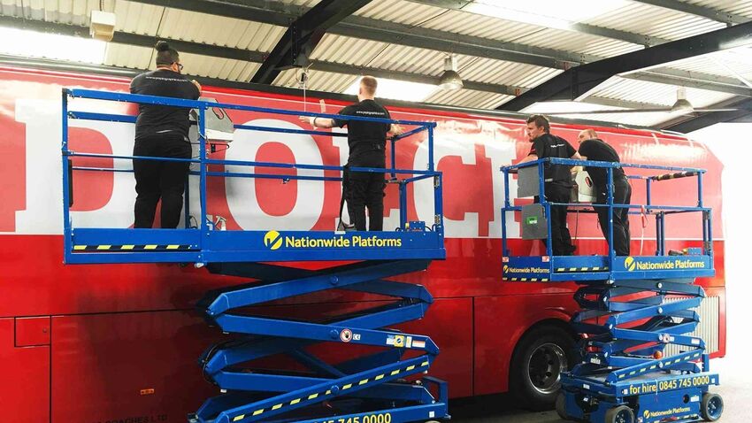 Red vehicle livery being professionally installed on FA Wales football team coach at Popin in Cardiff.