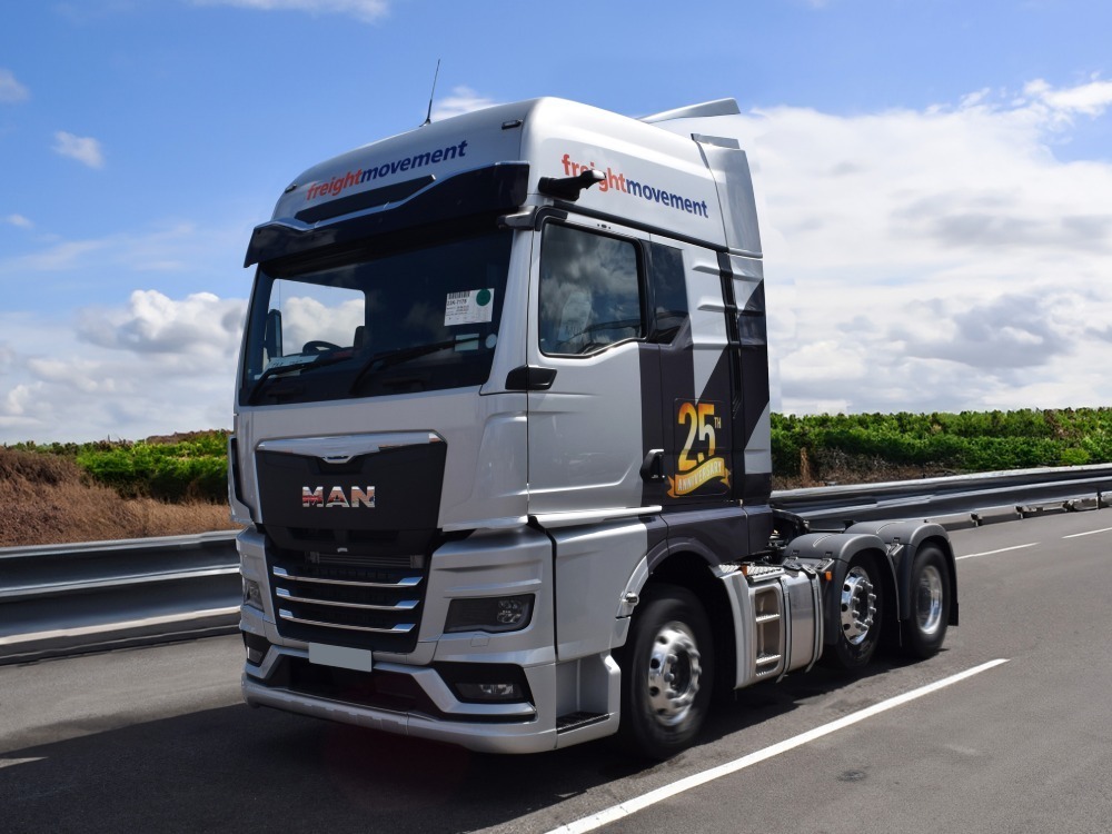 Vehicle wrap and graphics on a MAN lorry driving along a road.
