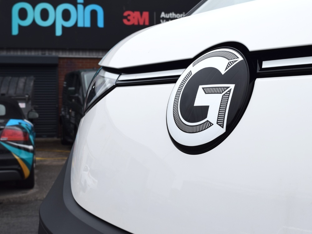 Close up of vinyl graphic details on company branded Volkswagen ID. Buzz electric vehicle with Popin sign in background in Cardiff.