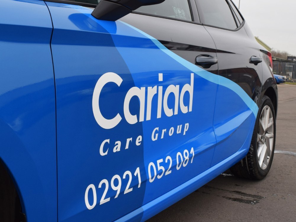 White branded vinyl graphics on side of blue and black SEAT Ibiza company car.