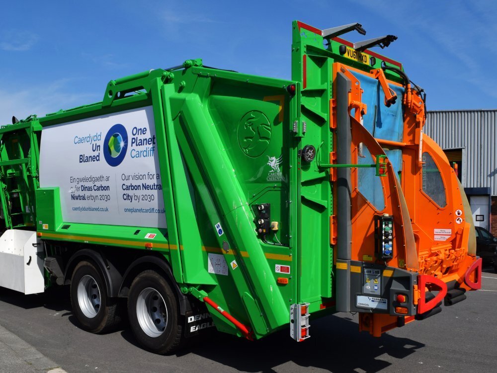 Green and orange wrap newly installed on a Dennis truck.