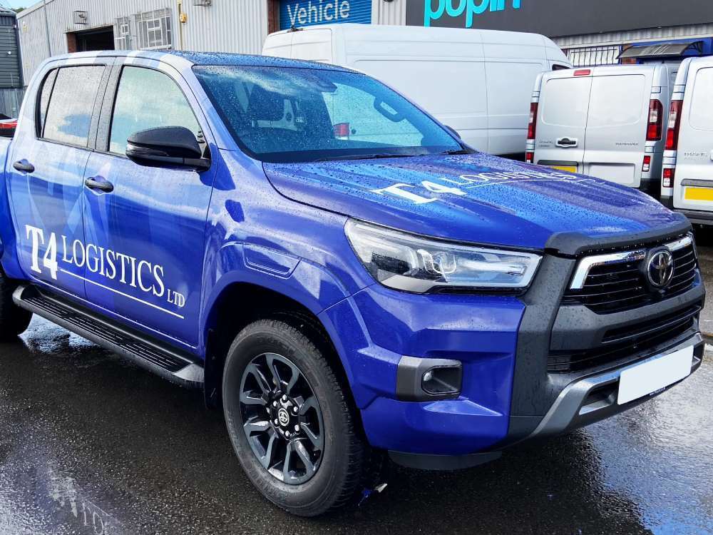 Toyota Hilux company car with blue vehicle wrap and white branded vinyl graphics.