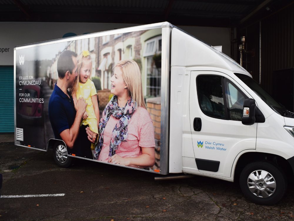 Large marketing campaign graphic installed on the side of a white Citroen Relay exhibition van.