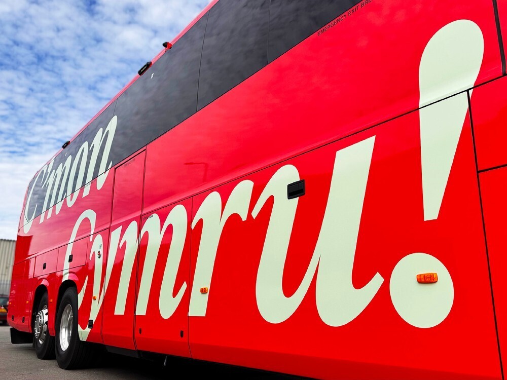 C'mon Cymru vinyl graphics messaging on red Scania Iriziar FAW football team coach.