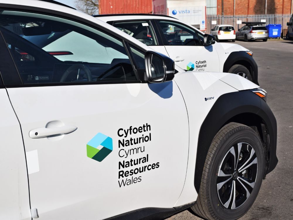 Branded Natural Resources Wales vinyl graphics installed on fleet of white Toyota bZ4X electric company cars.