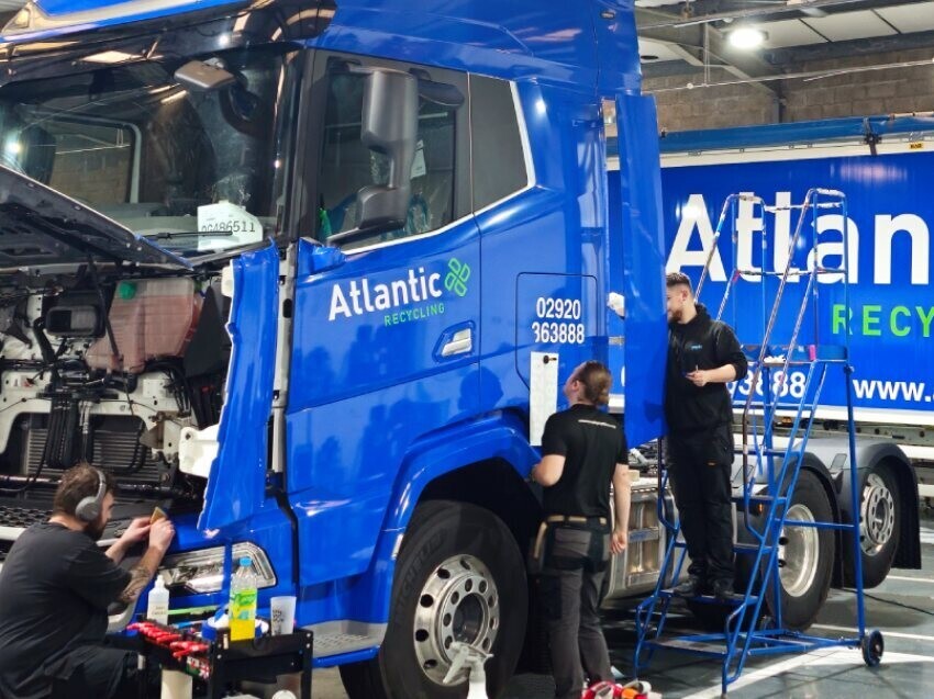 Vehicle vinyl wrap installers fitting livery and graphics to large lorry cab.