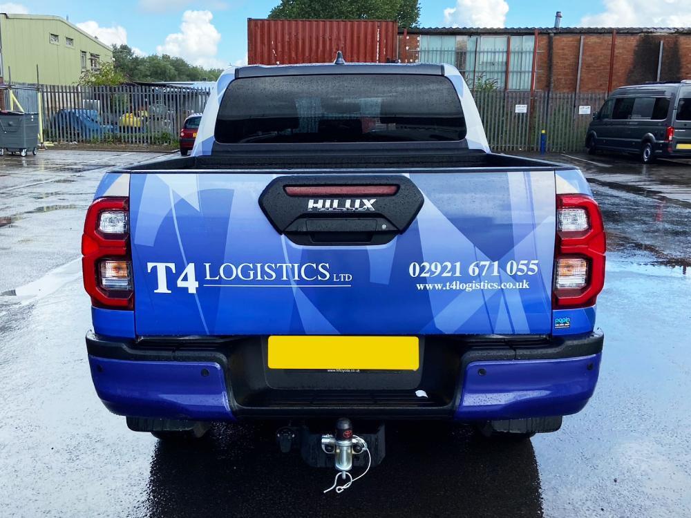 Rear end of Toyota Hilux company car with blue vehicle wrap and branded vinyl graphics.