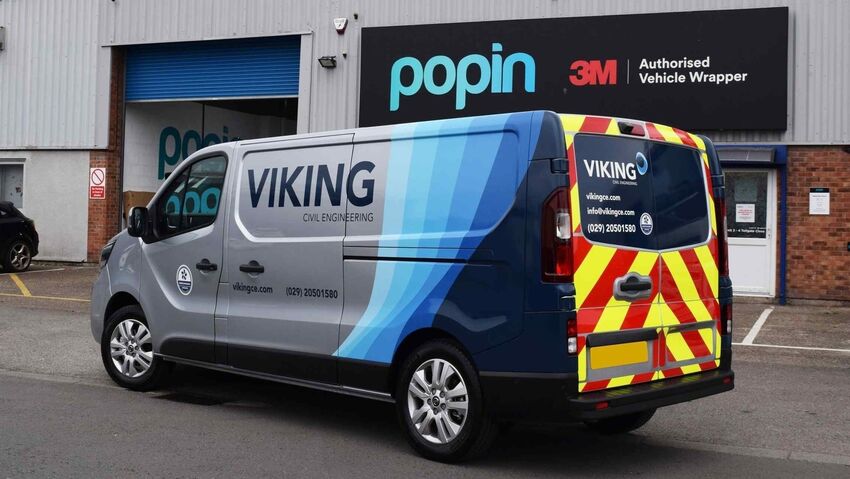 Company van with partial wrap and chevron markings on the rear of the vehicle and vinyl graphics on the front.