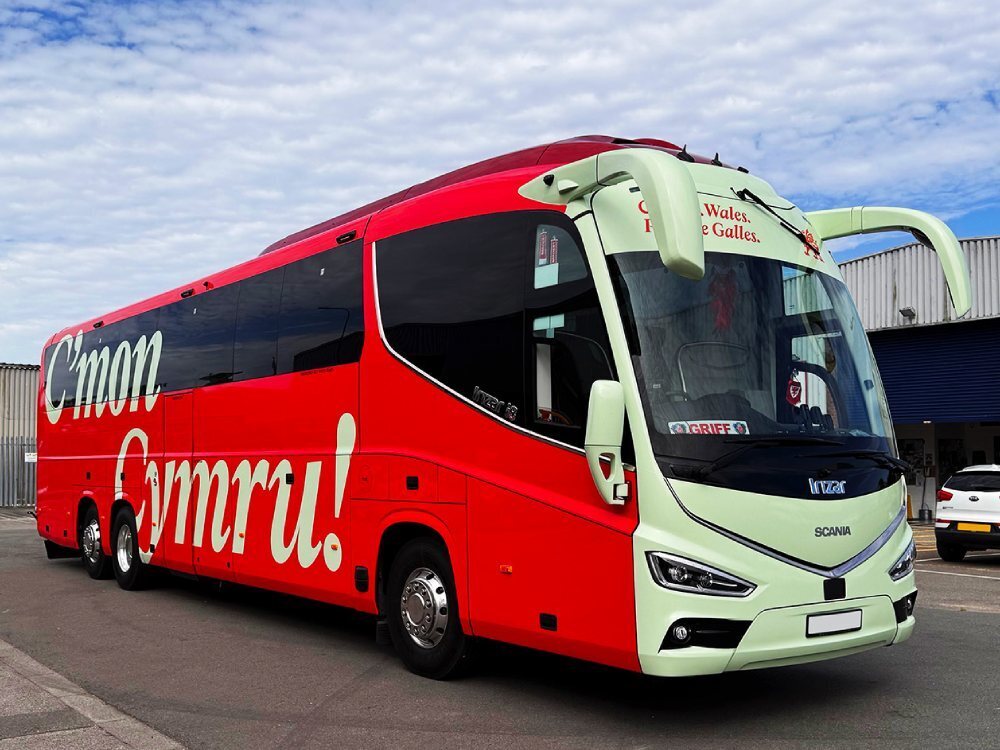 Branded red and green livery and graphics on FAW Scania Irizar football team coach.