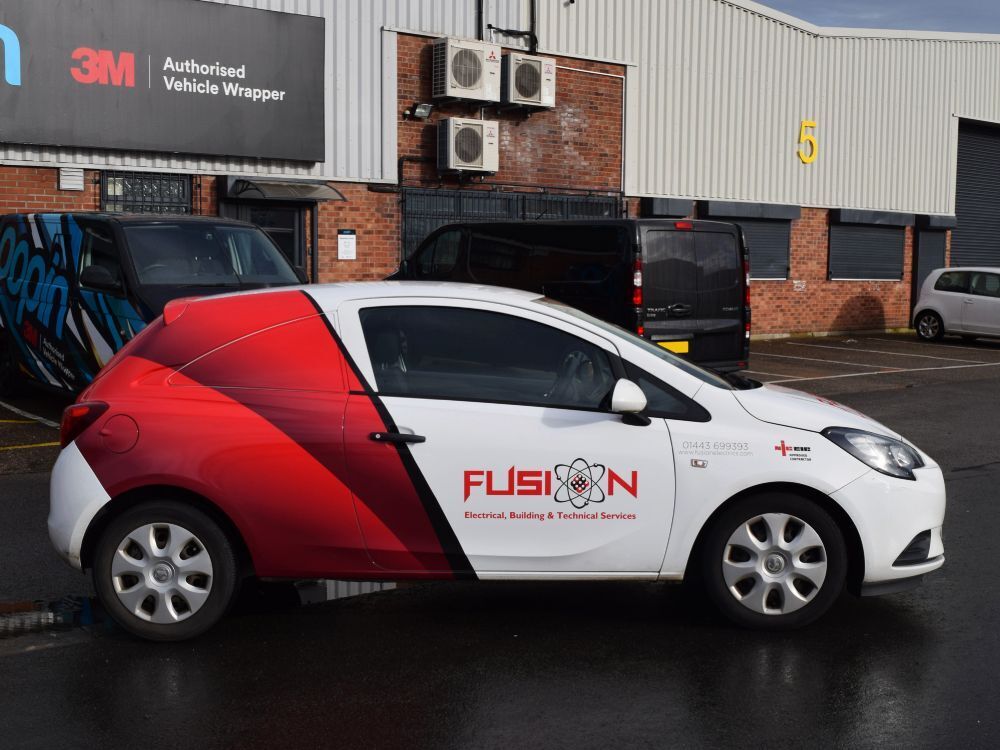 Partial red vehicle wrap and branded graphics on white company Vauxhall Corsa car.