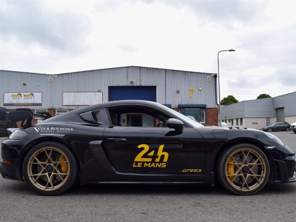 Black motorsport wrap and yellow race graphics on Porsche GT4 RS