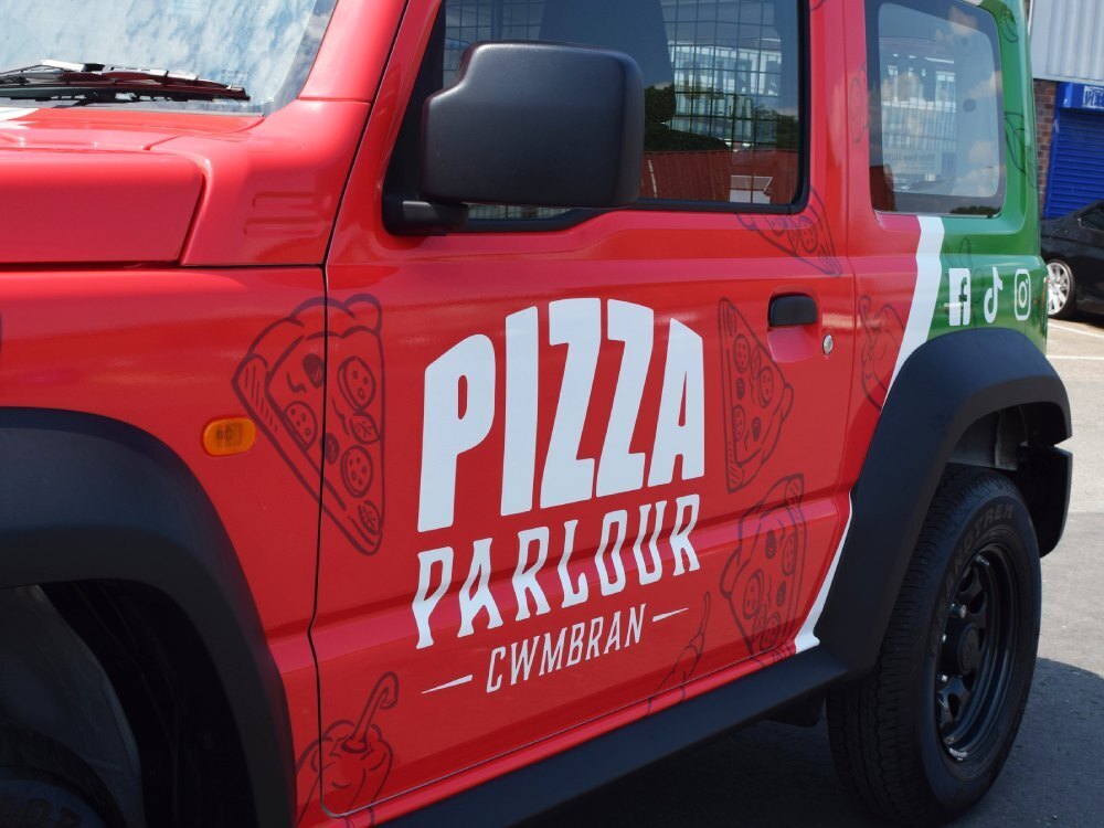 Vehicle wrap and branded Pizza Parlour company graphics on side of Suzuki Jimny.