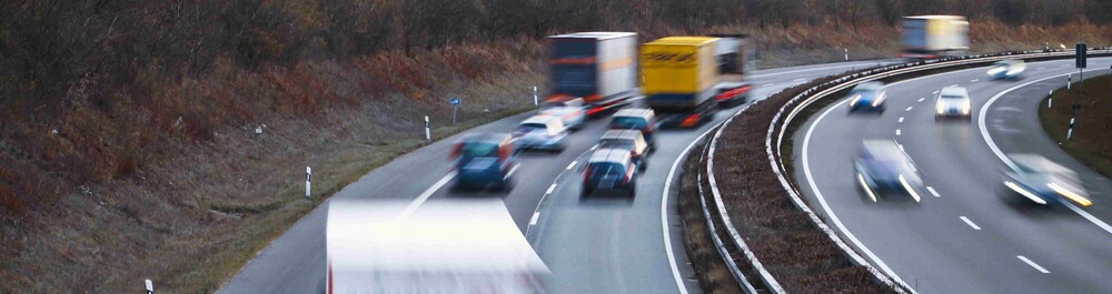 Branded HGV trucks driving fast along motorway.