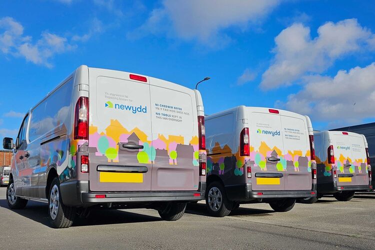 Fleet of company vans with matching partial vehicle wraps and vinyl graphics.