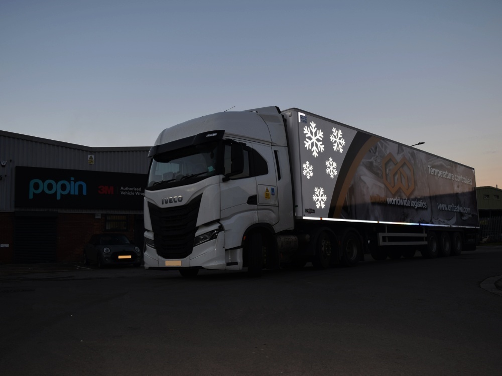 Snowflake reflective vinyl graphics on an IVECO truck at night.