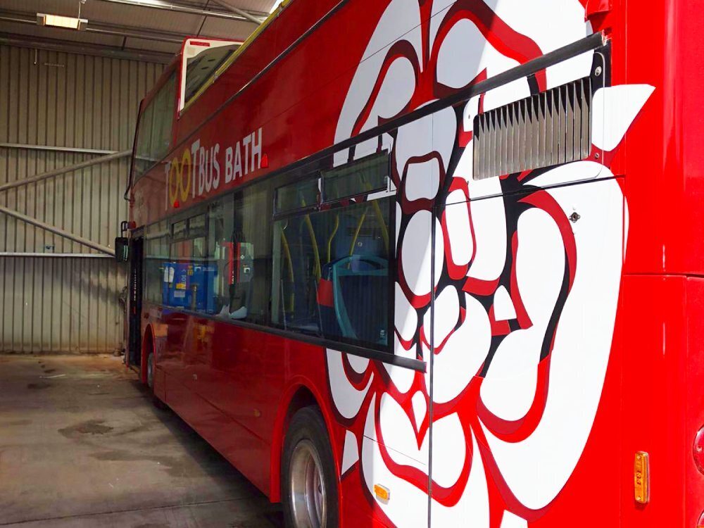 Close up of flower vinyl graphics design on red Tootbus Bath Optare VLE open top bus.