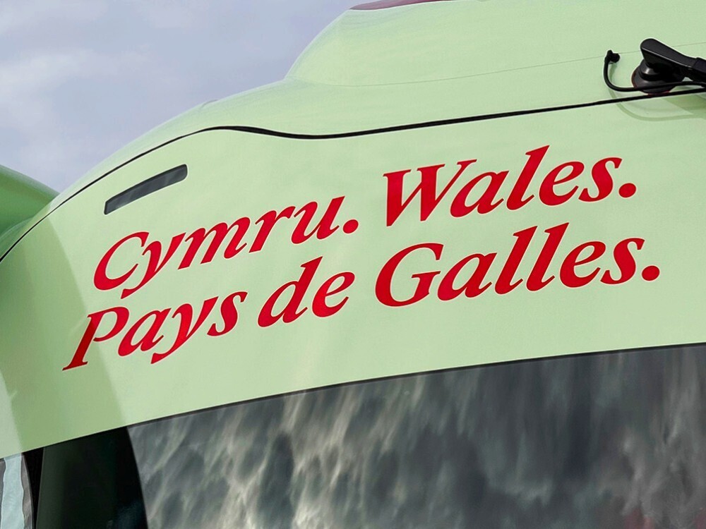 Red branded vinyl graphics and green livery on FAW Scania Irizar football team coach.
