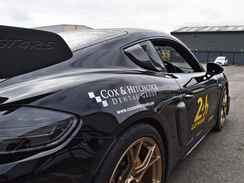 Branded company vinyl graphics on black Porsche GT4 RS.