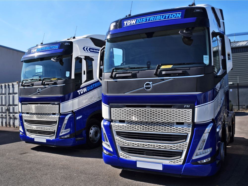 Matching vehicle wraps and branded company graphics on Volvo lorries.