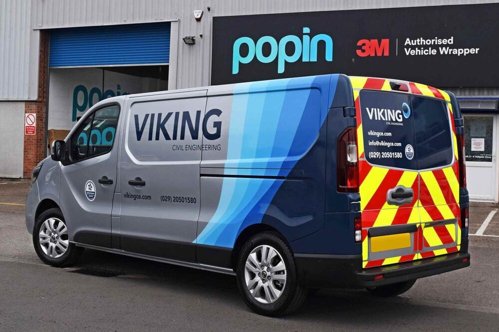 Silver van with partial vehicle wrap and graphics for business branding.