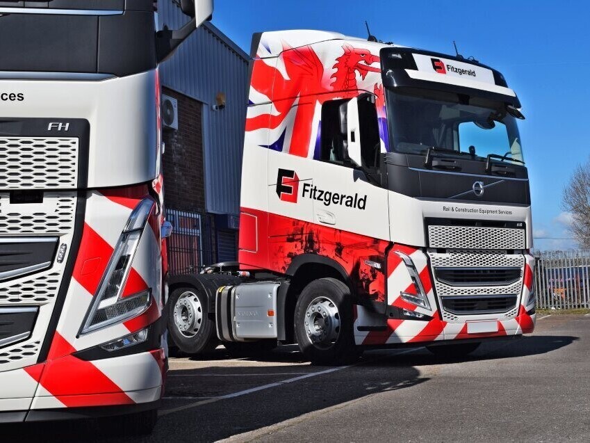 Fleet of Volvo lorries with matching red and white vinyl wraps.