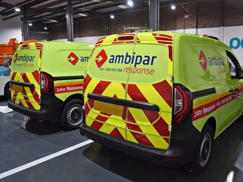 Two Renault Kangoo vans with matching yellow wraps and chevron graphics.
