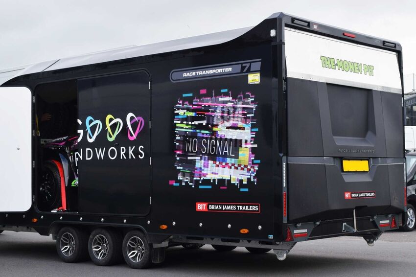 Colourful temporary vinyl graphics on a black motorsport trailer.