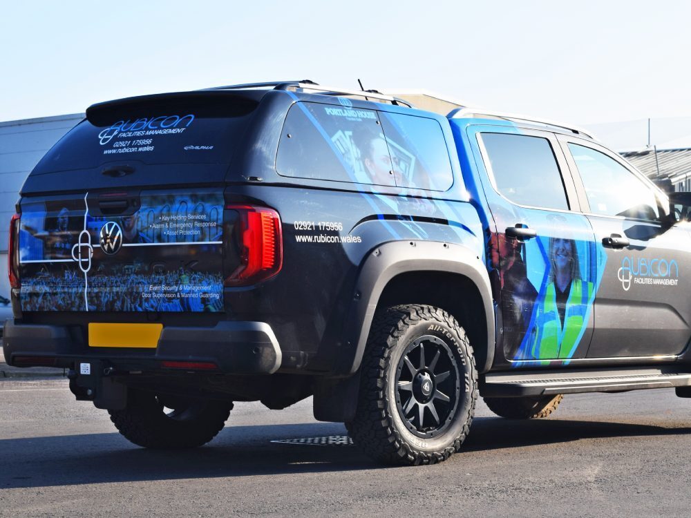 Branded partial vehicle wrap on rear end of Volkswagen Amarok company car.