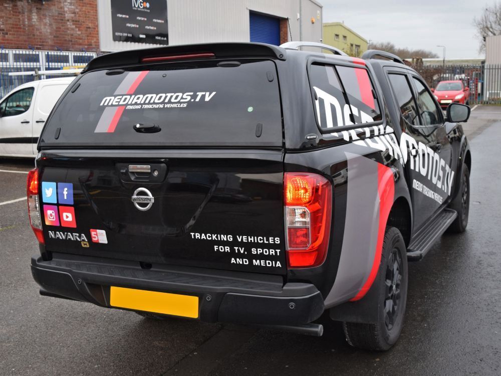 Rear of black company Nissan Navara with branded vehicle graphics.