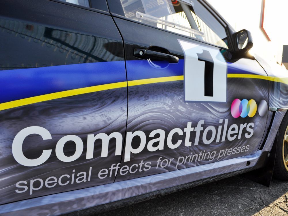 Close up of branded vehicle wrap on door of Subaru Impreza B13 company car.