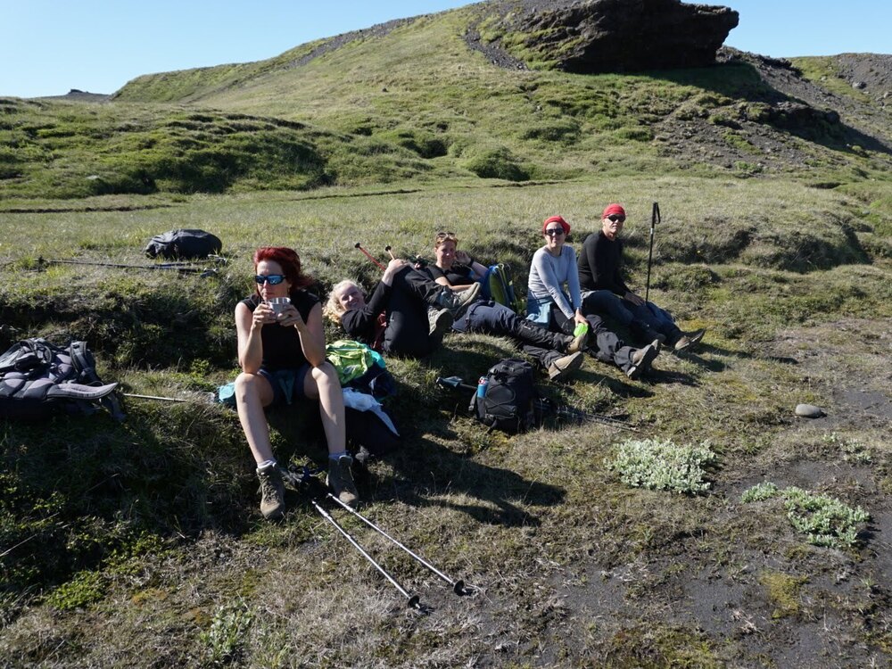 Hiking group resting on mossy lava in Hornstrandir Nature Reserve, Iceland – remote trekking