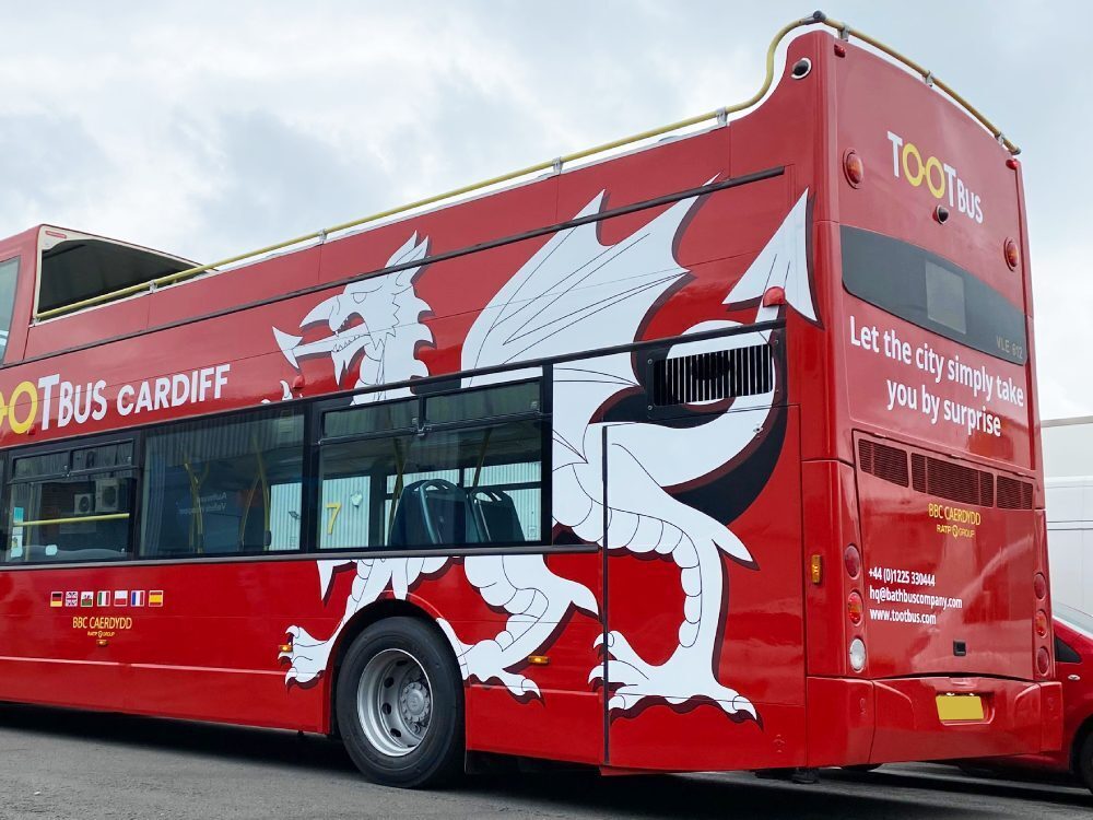 White dragon vinyl graphics design on red Tootbus company branded Ayats Bravo city open top bus.
