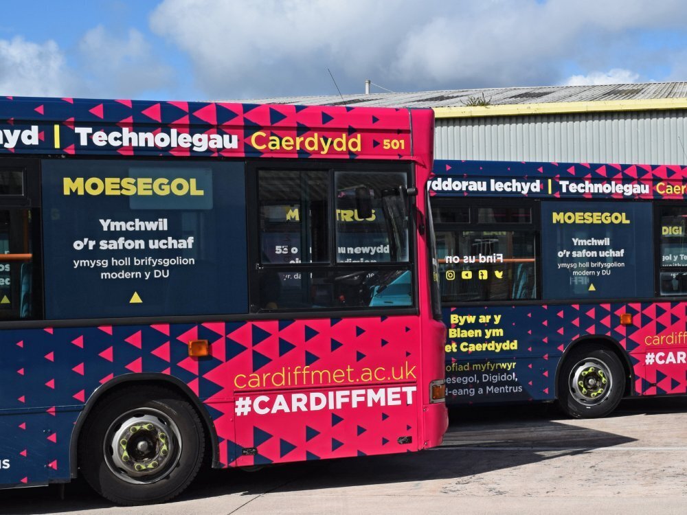 Company branded vehicle wrap and promotional graphics on side of Dennis Dart buses.