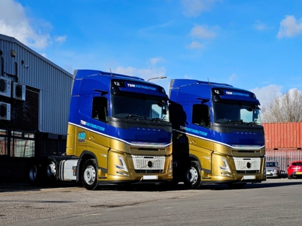 Fleet of Volvo trucks with matching blue and gold liveries.