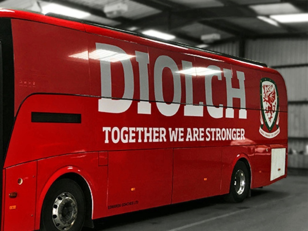 FA Wales branded vehicle graphics installed on side of red Caetano Levante coach.