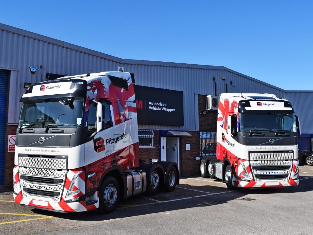 Matching red and white vehicle liveries and vinyl graphics on Volvo lorry cabs outside Popin in Cardiff.