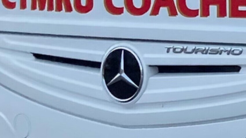 Mercedes badge on the front of a white coach.