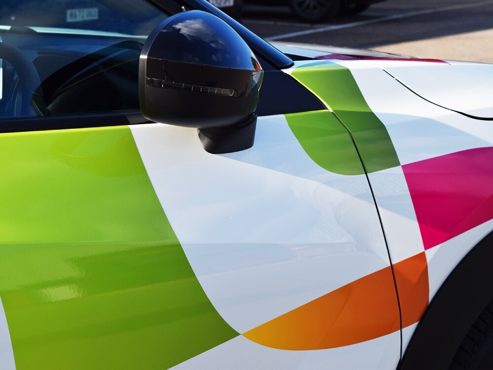 Colourful business branded vehicle graphics on Nissan Juke hybrid company car.