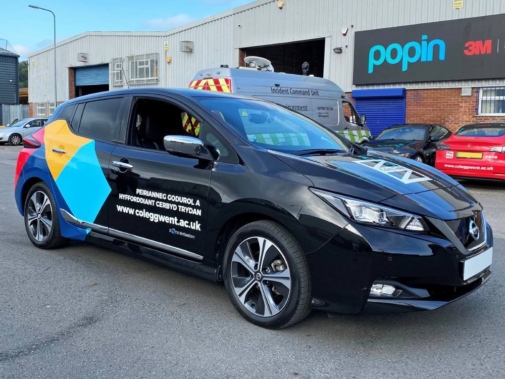 Branded partial vehicle wrap and graphics on company Nissan Leaf.