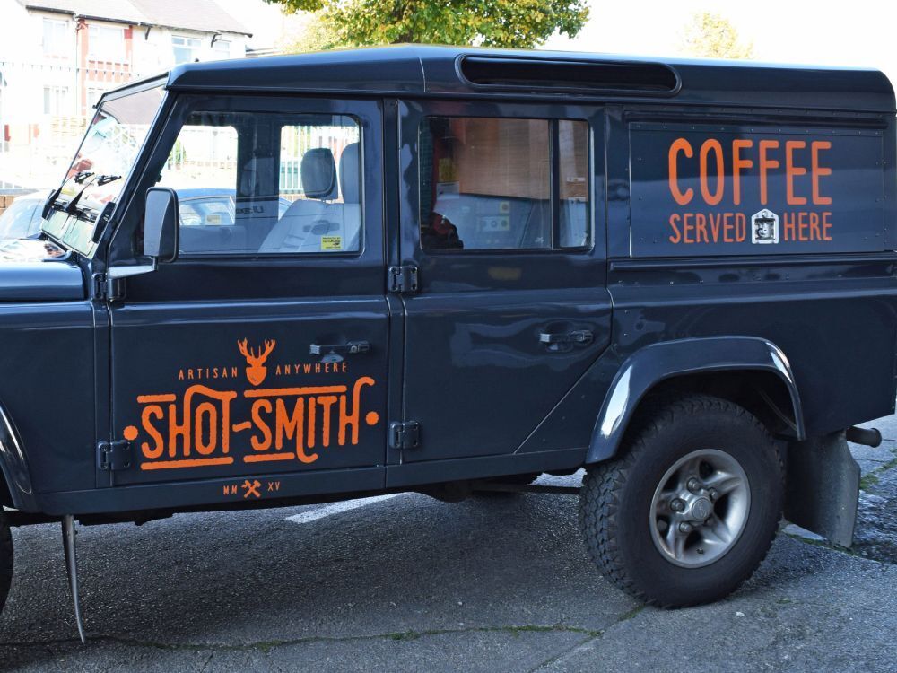 Orange company branded vinyl graphics installed on side of Land Rover Defender.
