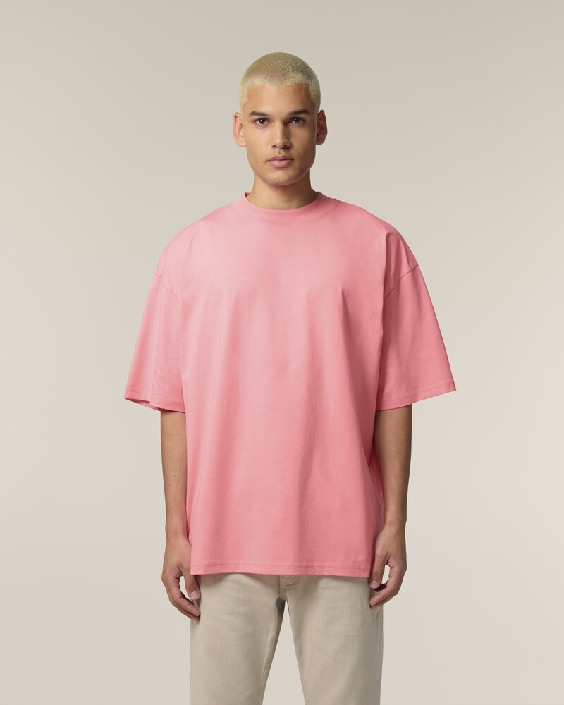 Male model in unisex Pink Joy Blaster 2.0 Stanley/Stella oversized t-shirt and beige trousers, ideal for eco-friendly garment printing.
