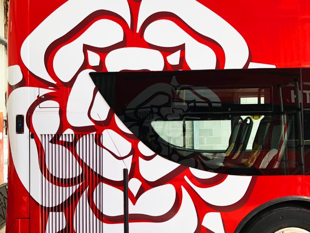 Close up of white flower vehicle vinyl graphics installed on red UNVI Urbis open top tour bus.