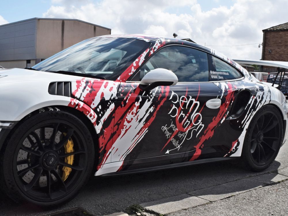 White Porsche GT3 RS company car with branded vehicle wrap.