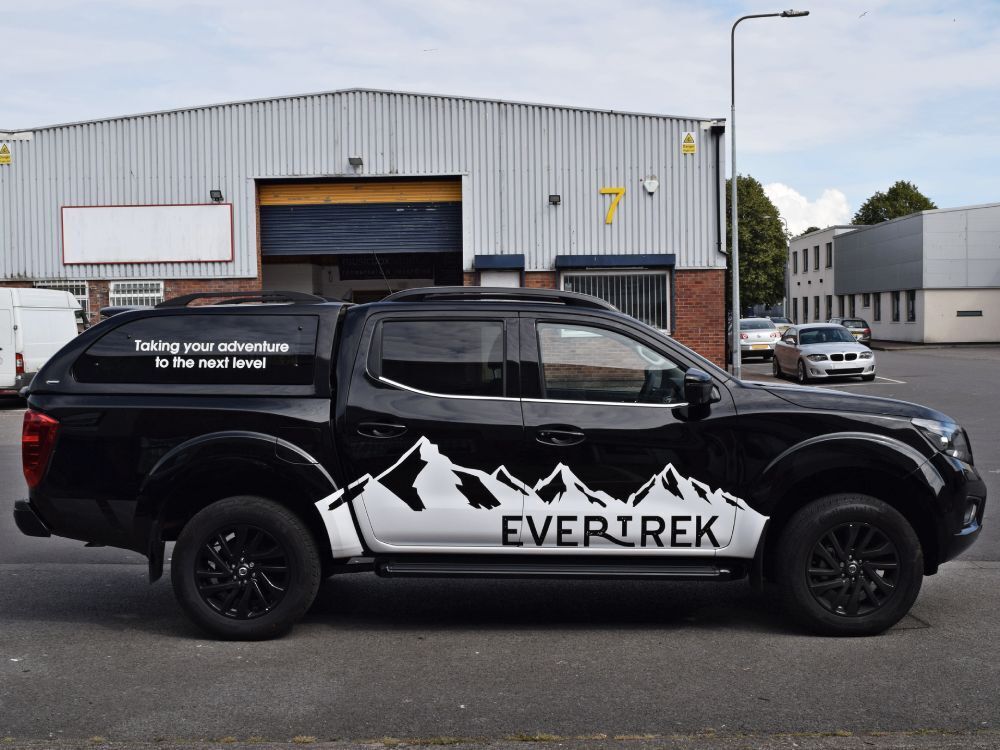 Company black Nissan Navara with branded mountain themed vinyl graphics.