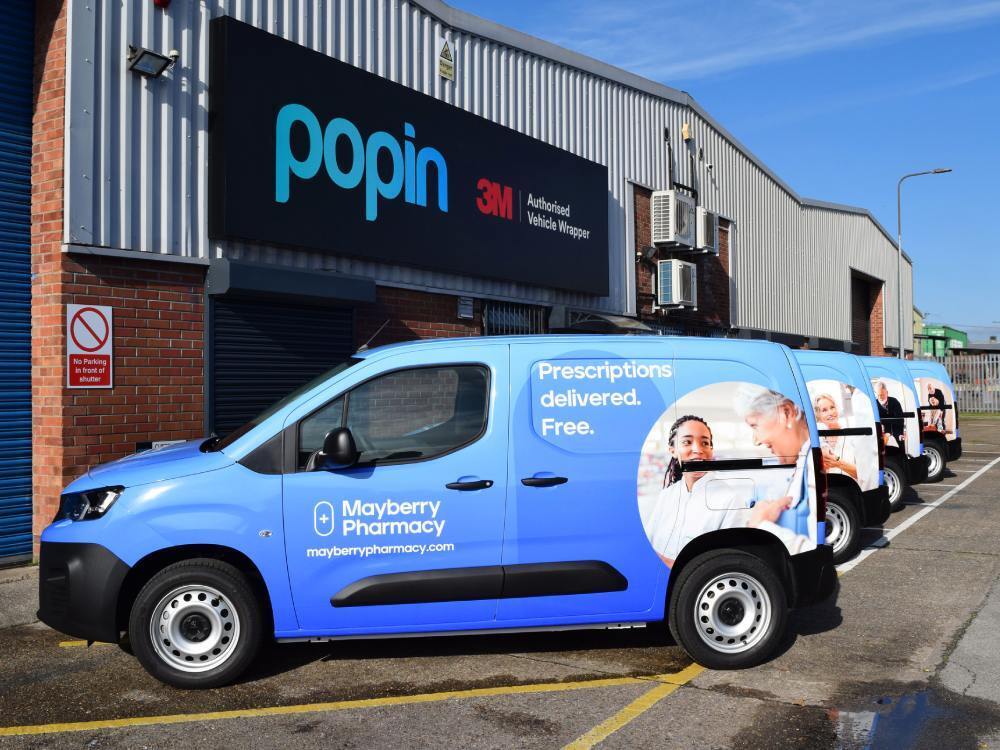 Fleet of blue Peugeot Partner vans with matching vehicle wraps.