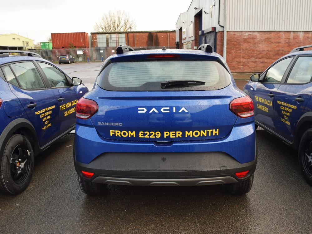 Fleet of blue company Dacia Sandero cars with yellow vinyl graphics.