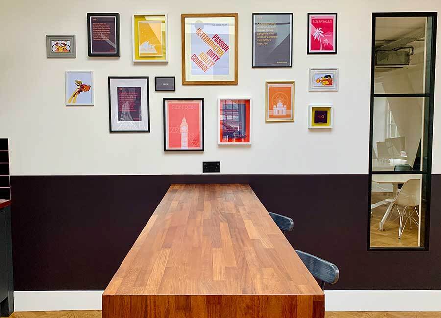 Media Office in London with a wooden Breakfast Bar and a glazed window looking into a meeting room with branded picture wall