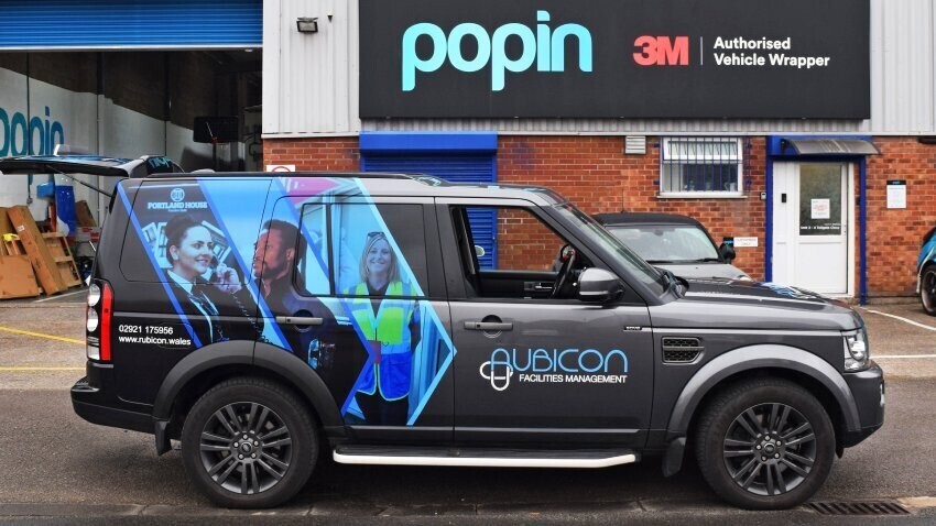 Grey company Land Rover Discovery with branded partial vehicle wrap outside Popin in Cardiff.