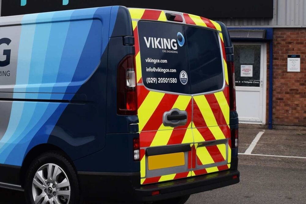 Reflective chevron graphics installed on rear of engineering work van for safety and compliance.