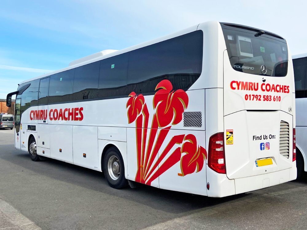 Rear view of white Mercedes Tourismo coach with red vinyl graphics for Cymru Coaches.